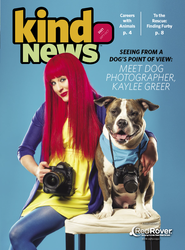 Kind News, Jr. September October 2021 cover. Photographer with red hair, holding camera with arm around pitbull dog. Dog has a camera around their neck as well.