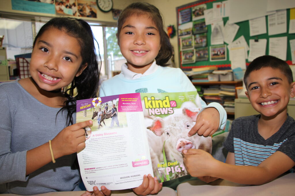 Three students holding Kind News magazine